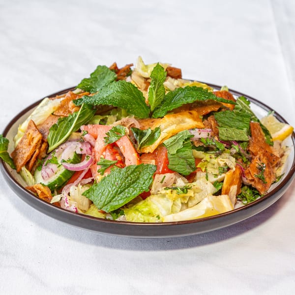 Colorful fattoush salad with lettuce, tomatoes, cucumbers, red onions, mint, and crispy pita bread.
