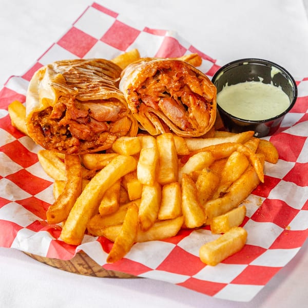 Two savory wraps, golden french fries, and a side of green dipping sauce on checkered paper.